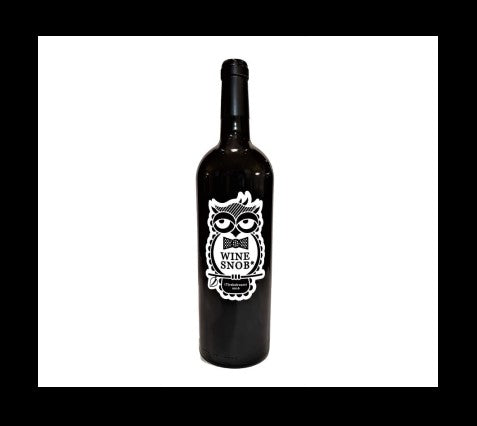 Bordeaux-style bottle with the Wine Snob* 2016 (T)rebelrouser label showing an owl perched on a stick with a leaf, slightly rolling its eyes, and wearing a black bowtie with white polka dots.